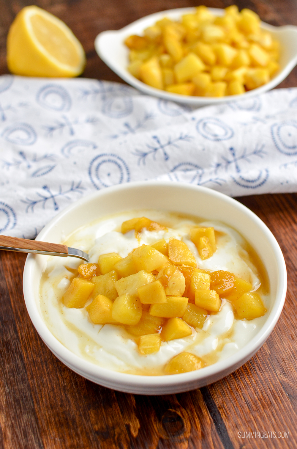 roast pineapple and mango in white bowl with Greek yoghurt and spoon