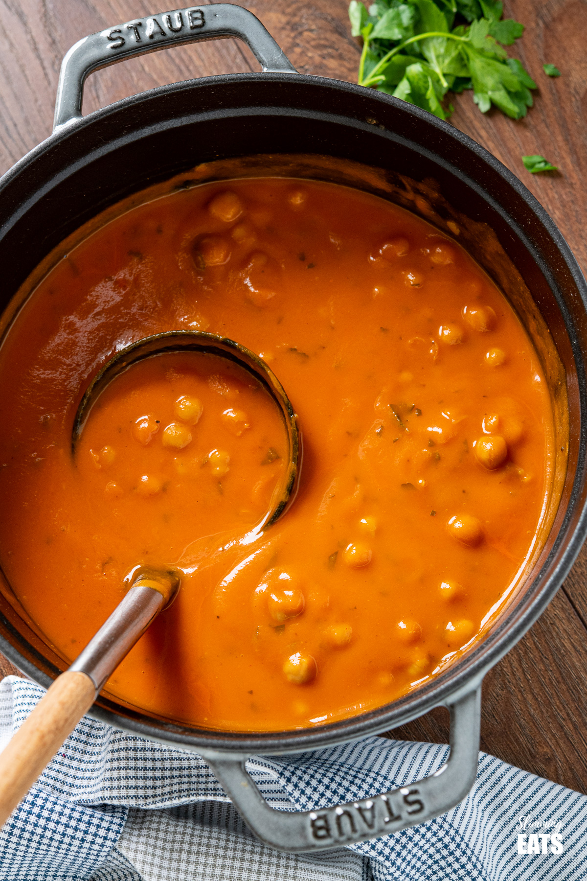 close up of Chickpea and Tomato Soup in grey staub cast iron pan with soup spoon