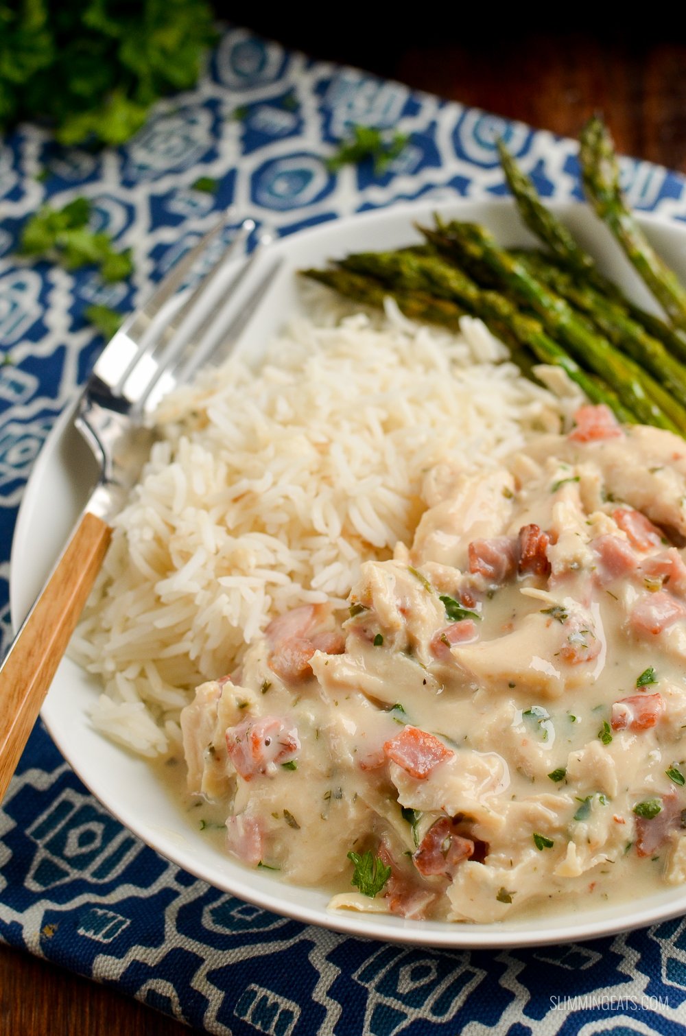 Healthier Slow Cooker Crack Chicken - the ultimate family-friendly creamy chicken recipe topped with the yummy smokey flavour of bacon. Oh my!! #slimming #weightwatchers #chicken #slowcooker #glutenfree #bacon #creamy close up of slow cooker crack chicken on white plate with rice and asparagus