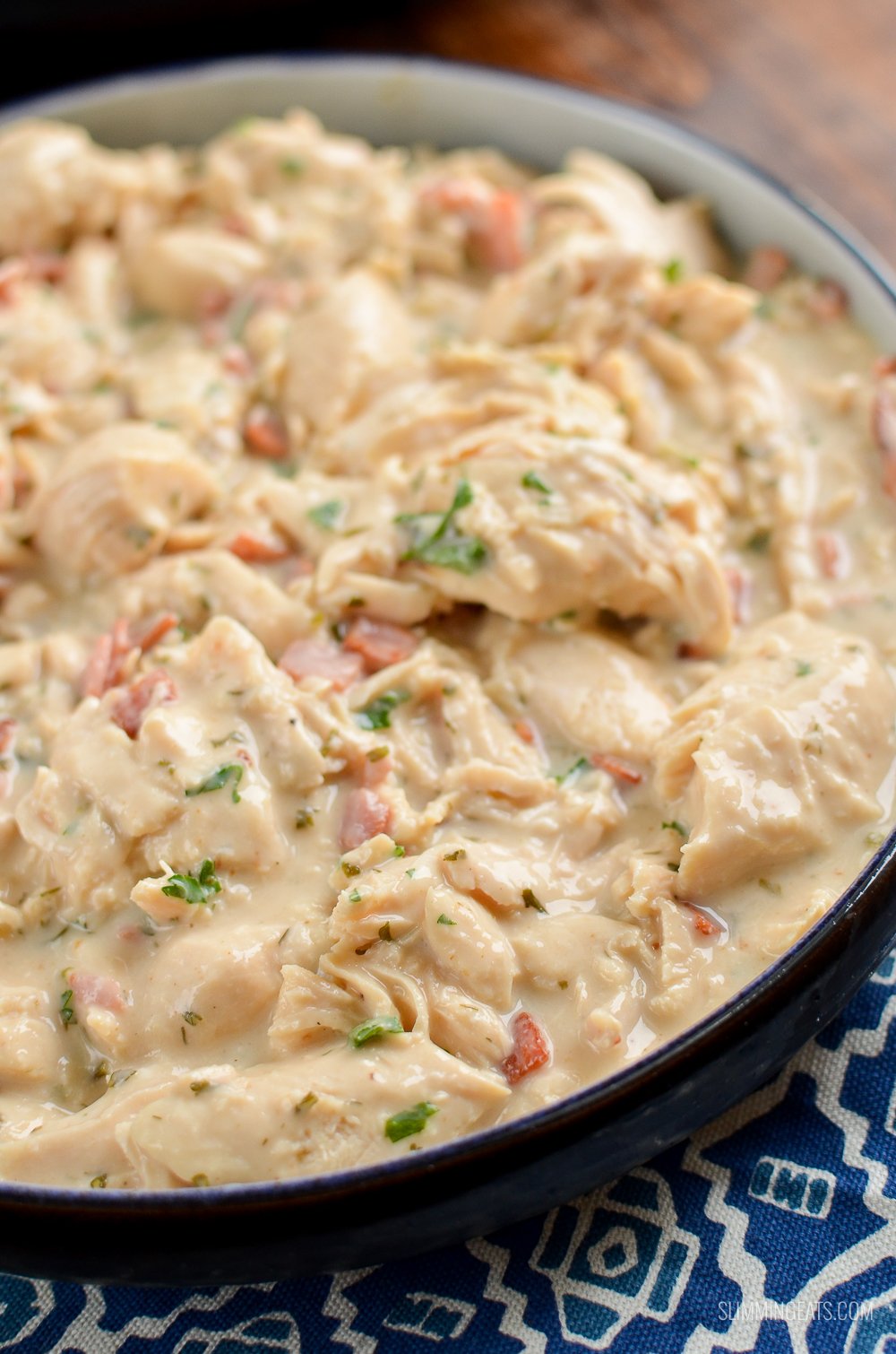 Healthier Slow Cooker Crack Chicken - the ultimate family-friendly creamy chicken recipe topped with the yummy smokey flavour of bacon. Oh my!! #slimming #weightwatchers #chicken #slowcooker #glutenfree #bacon #creamy slow cooker crack chicken in dish of blue patterned placemat