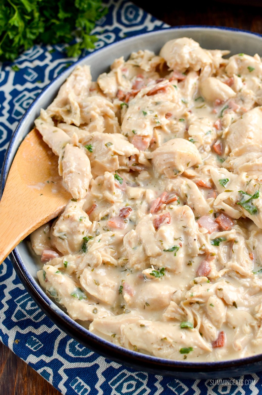 Healthier Slow Cooker Crack Chicken - the ultimate family-friendly creamy chicken recipe topped with the yummy smokey flavour of bacon. Oh my!! #slimming #weightwatchers #chicken #slowcooker #glutenfree #bacon #creamy slow cooker crack chicken in dish on blue patterned placemat