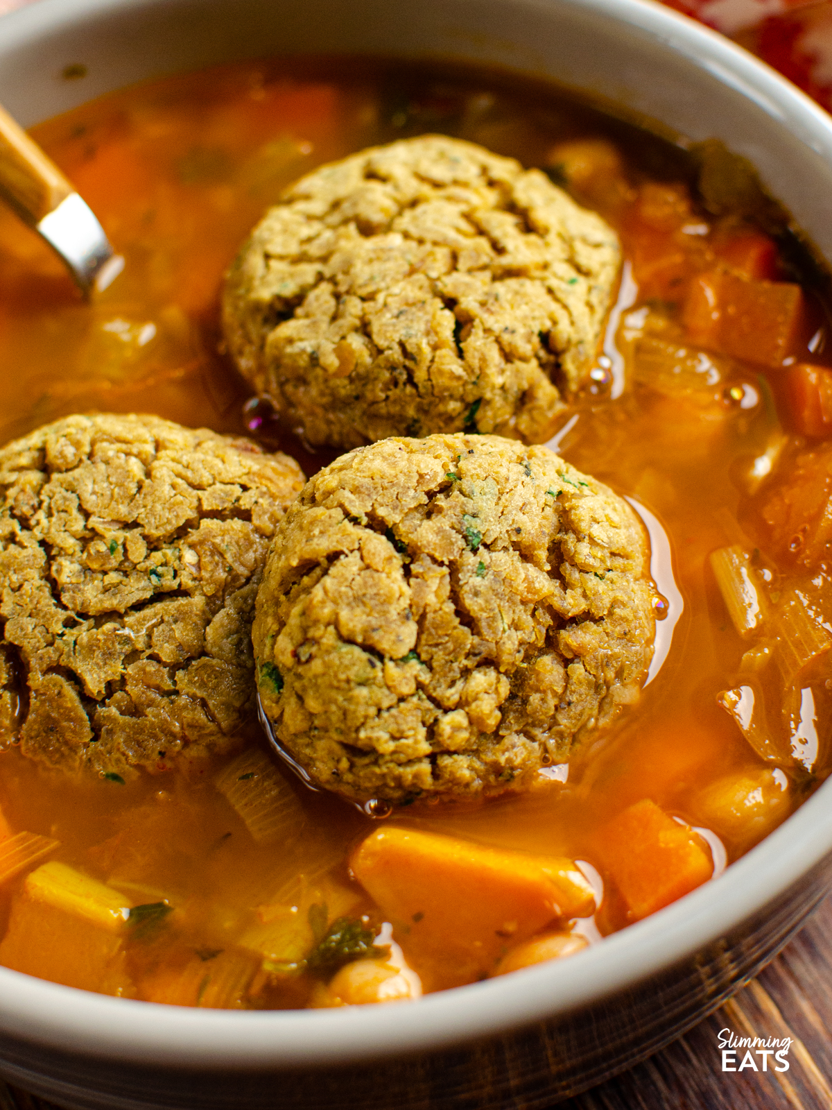 close up of vegan lentil dumplings placed in a grey bowl with vegetable bean stew