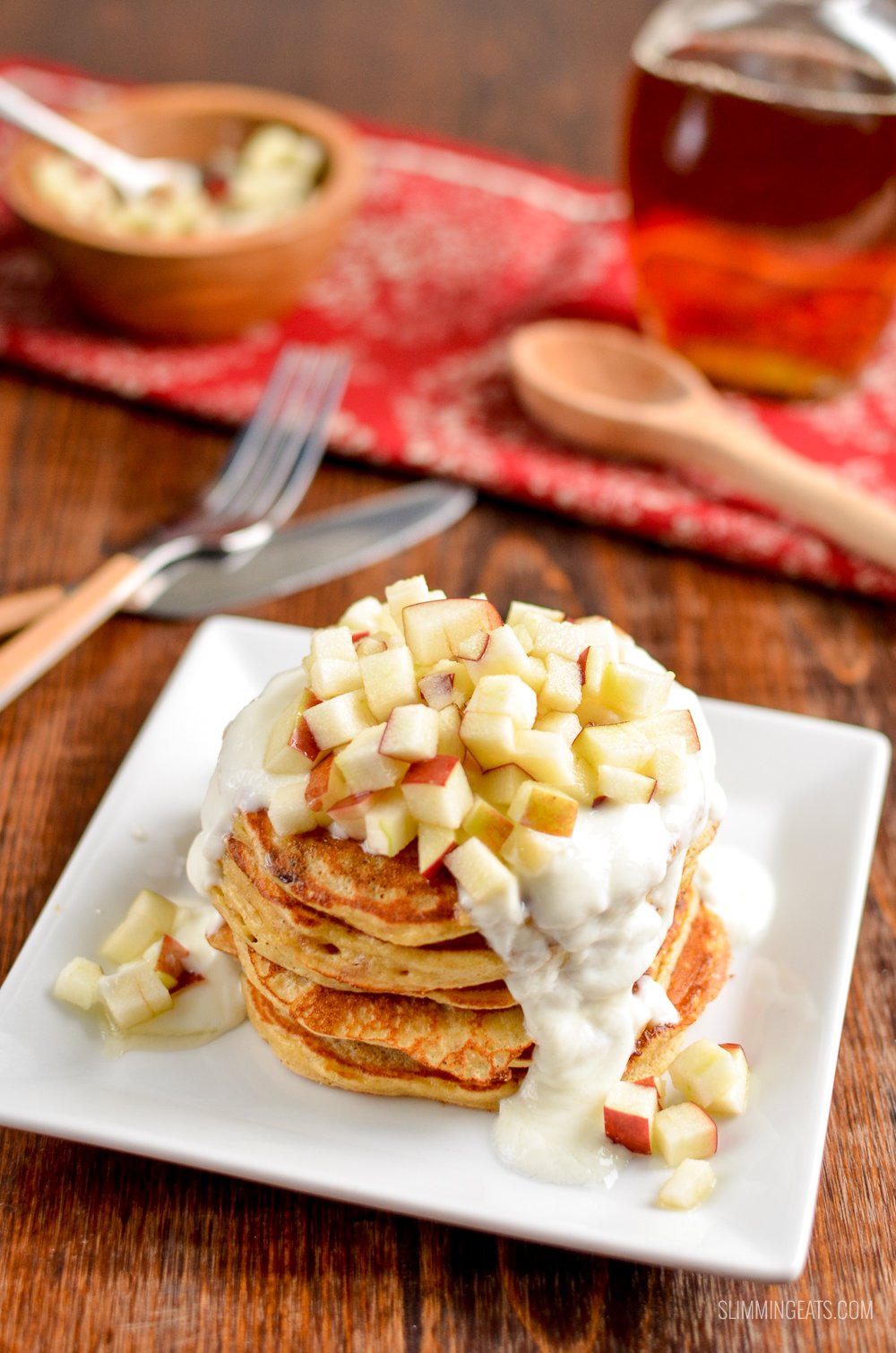 mince pie pancakes stack on white plate topped with apple, yoghurt and maple syrup