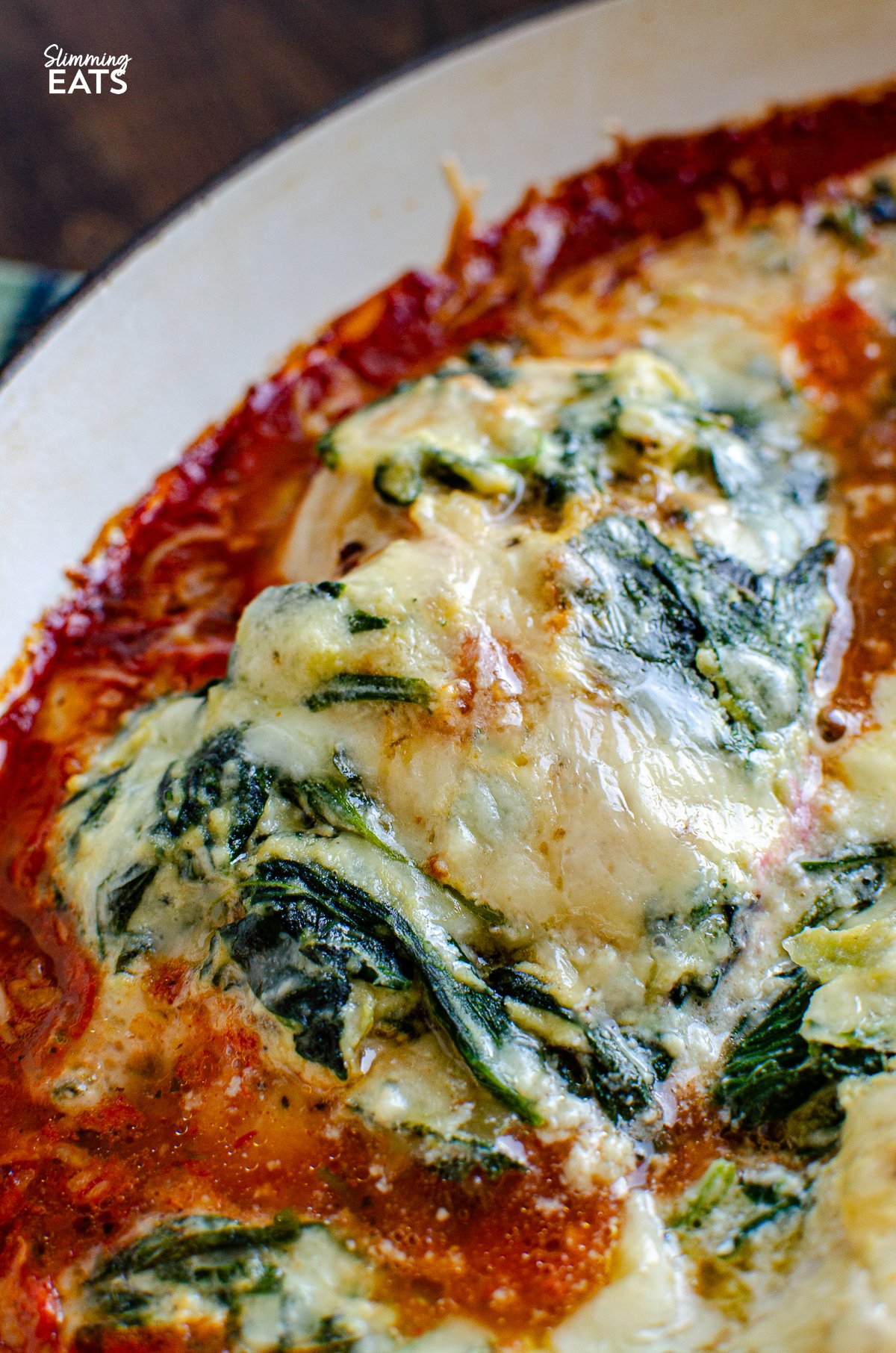 close up of Ricotta Spinach Topped Chicken in cast iron skillet with spatula