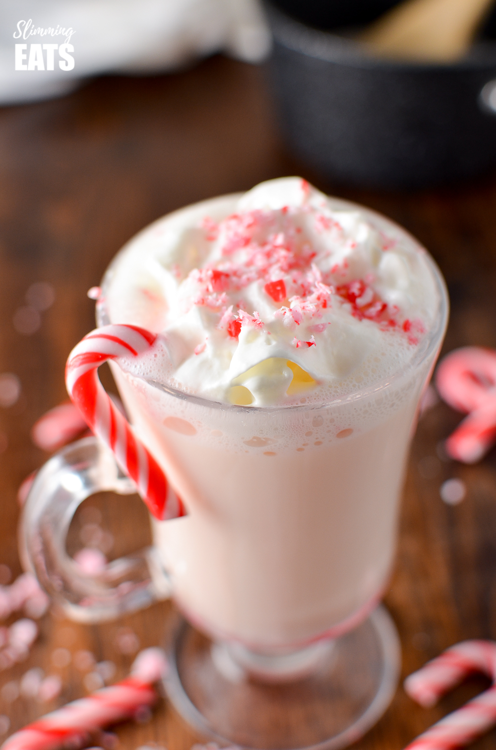 close up of candy cane white hot chocolate in glass mug with candy cane
