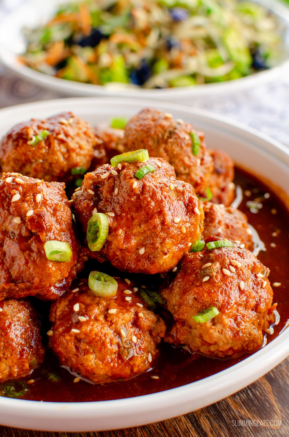 white bowl of firecracker chicken meatballs with stir fried vegetables in background