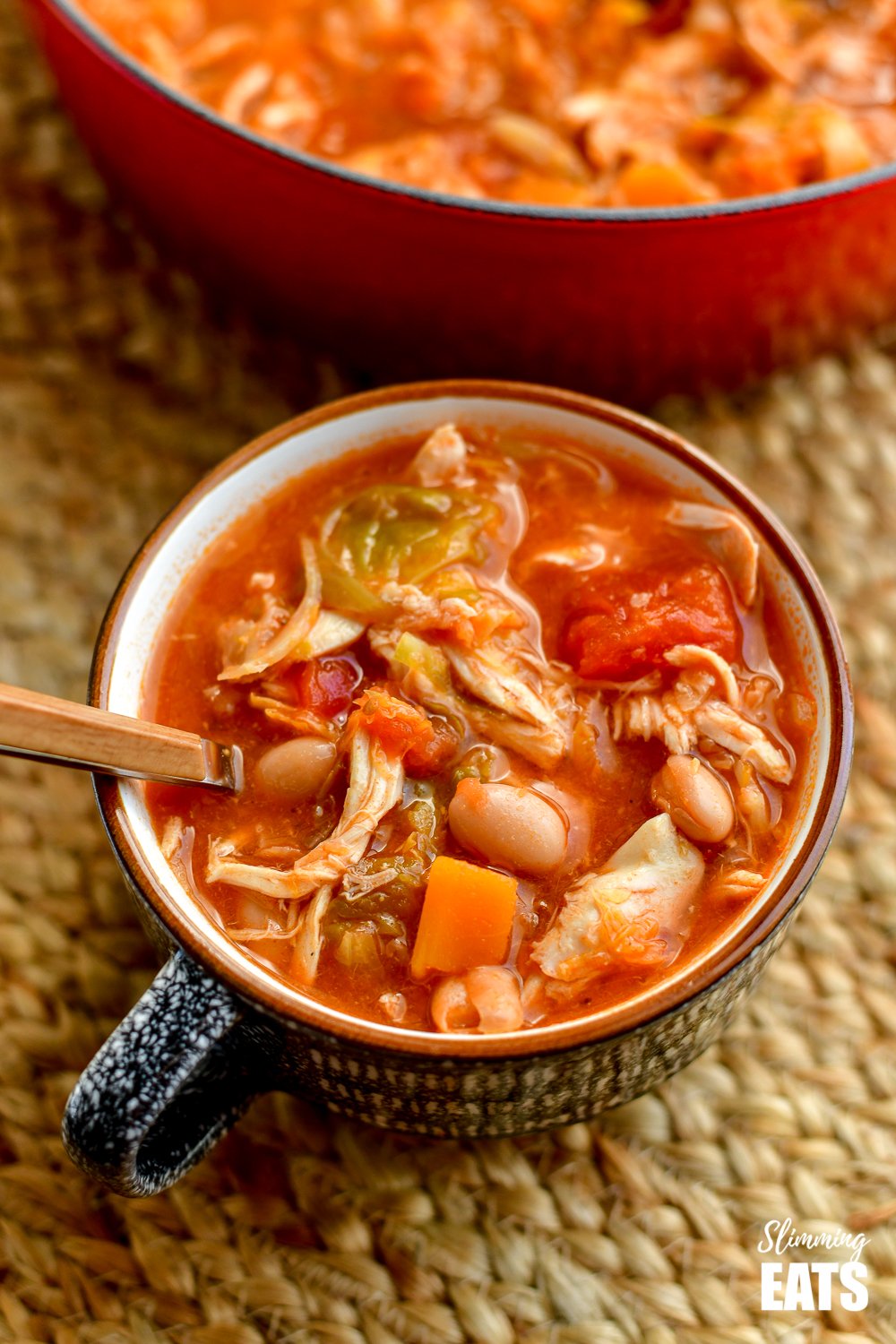 mug filled with Leftover Chicken Brussels Sprouts and Bean Soup with spoon place on mat