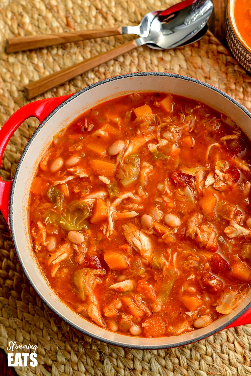 leftover chicken Brussels sprouts and Bean soup in dutch oven pot with spoons placed above. 