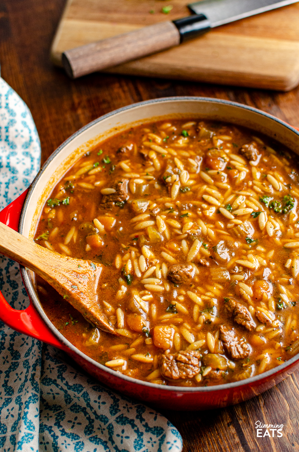 beef orzo stew in cerise cast iron pot with wooden spoon