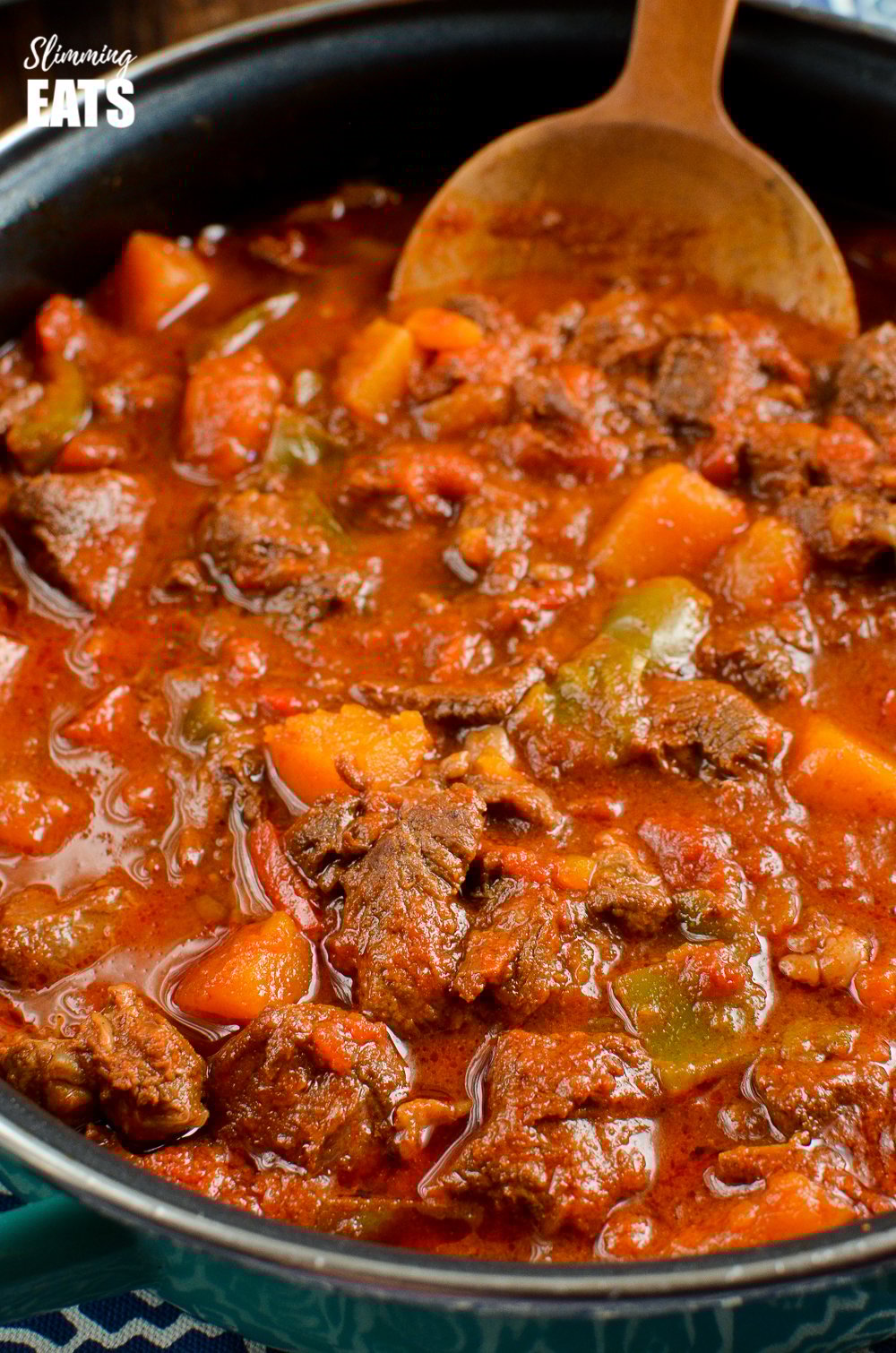 Paprika Beef - tender chunks of beef in a rich smokey paprika tomato sauce with chunks of butternut squash. #glutenfree #dairyfree #instantpot #slowcooker #slimmingeats #weightwatchers #beef close up of paprika beef in frying pan with wooden spoon