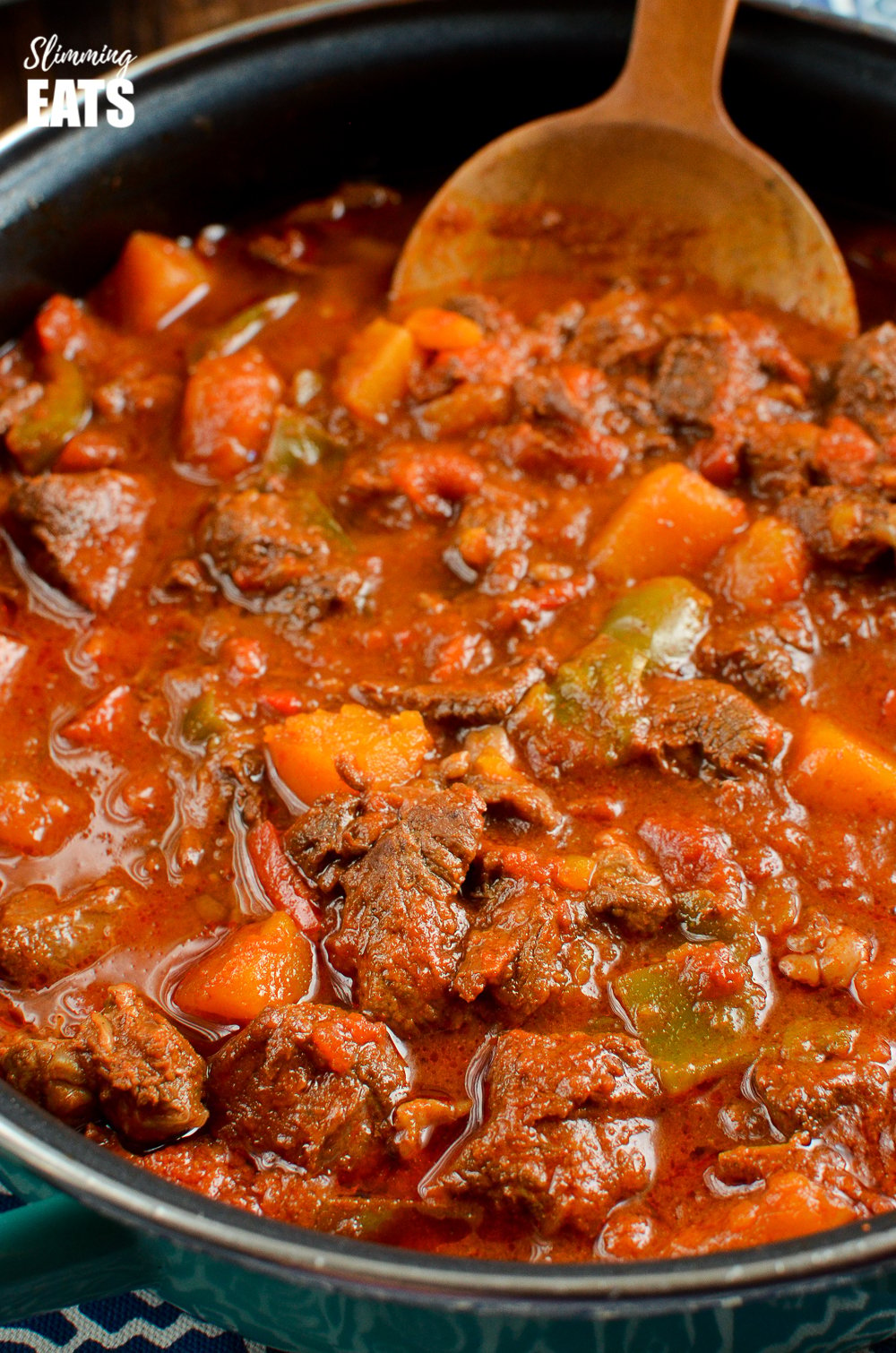 close up of paprika beef in frying pan with wooden spoon