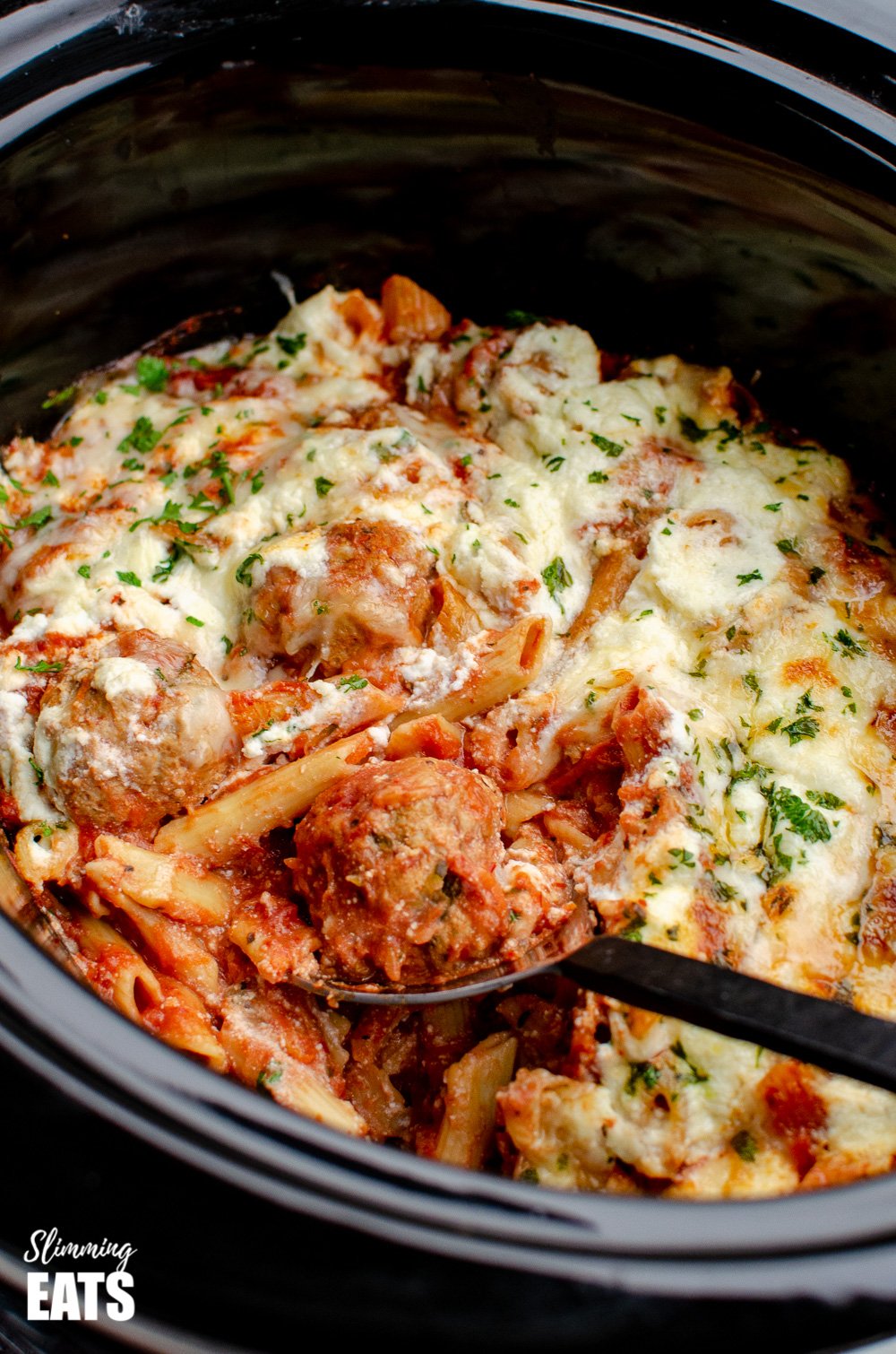 Slow Cooker Chicken Meatball Pasta Bake - a delicious recipe for easy tender chicken meatballs, combined with penne pasta and topped with ricotta and parmesan cheese. #slowcooker #slimmingeats #weightwatchers #chicken #pasta #crockpot #ricotta spooning meatballs out of slow cooker chicken meatball pasta bake