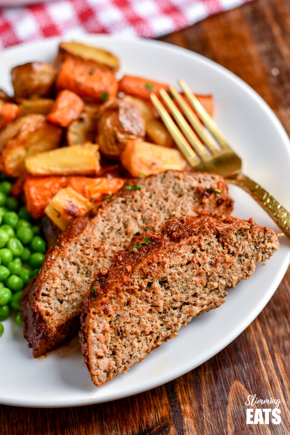 2 slices of slow cooker chicken mushroom meatloaf on white plate with roasted vegetables and peas