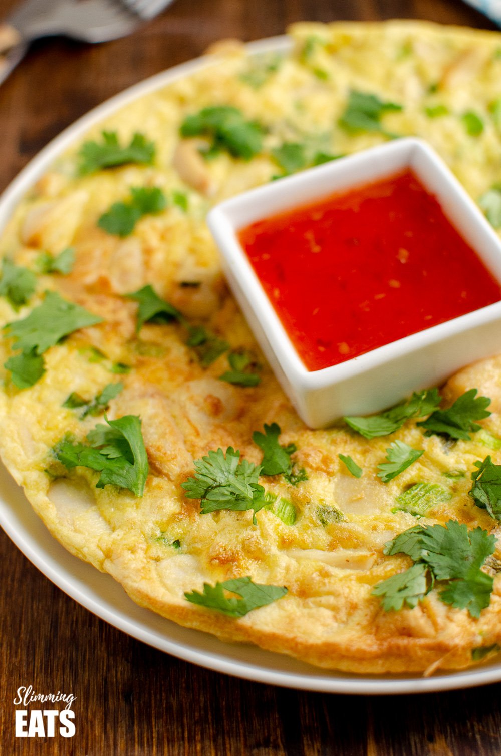 thai chicken omelette on white plate with sweet chilli sauce