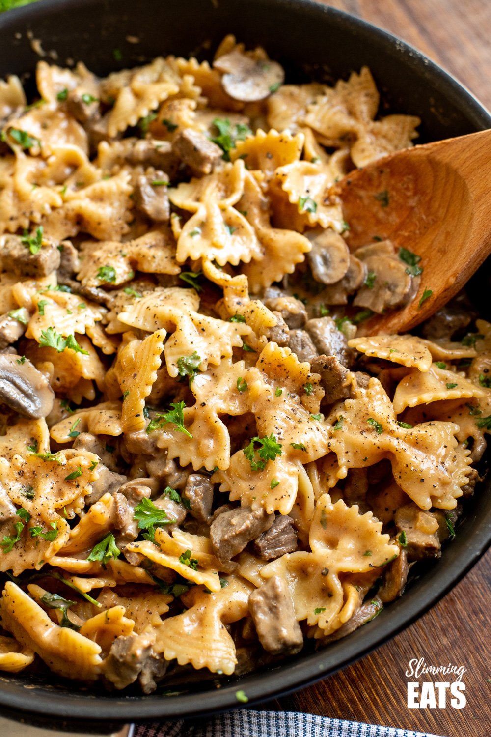 one pot beef stroganoff pasta in black frying pan with wooden spoon