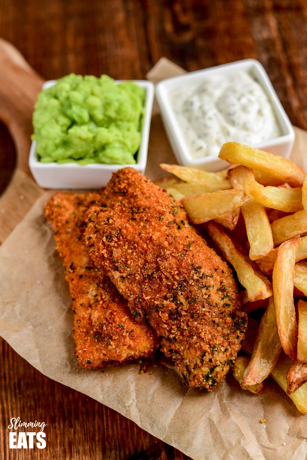 close up of actifry fish and chips with mushy peas and tartare sauce on parchment paper