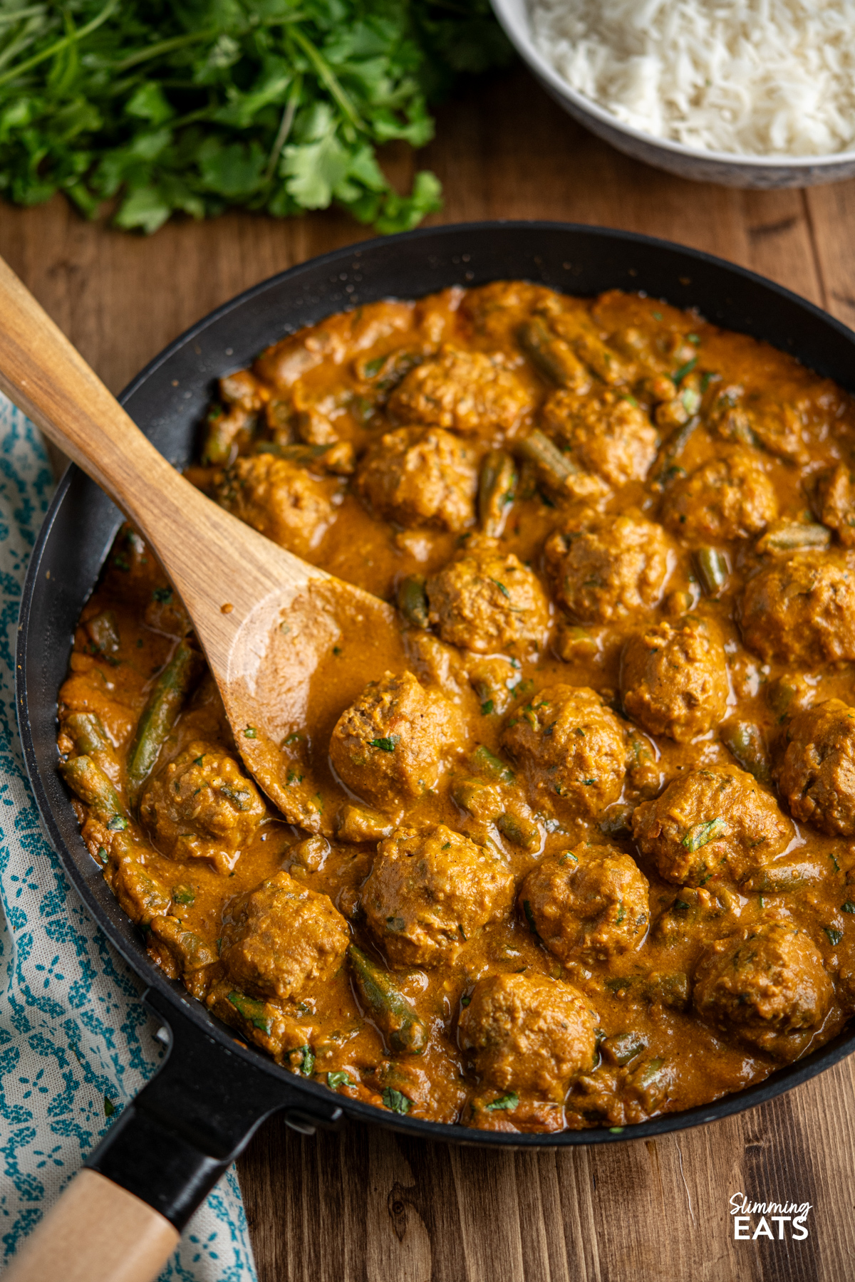 A Creamy Coconut Beef Meatball Curry - delicious tender meatballs with hidden veg in an amazing coconut sweet potato sauce. Gluten free, dairy free, paleo, whole30, Slimming and Weight Watchers friendly coconut beef meatball curry in black frying pan with wooden handle