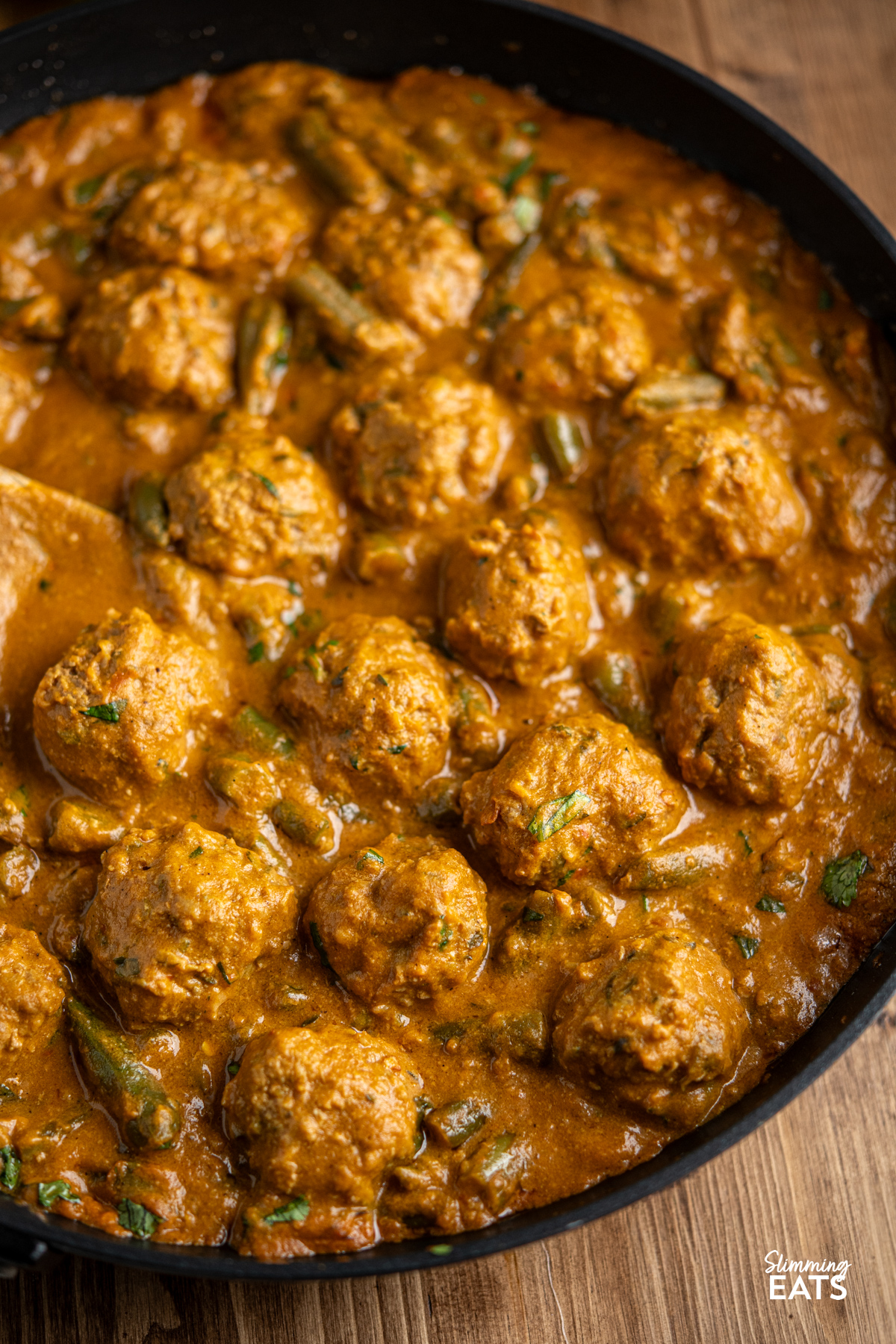 A Creamy Coconut Beef Meatball Curry - delicious tender meatballs with hidden veg in an amazing coconut sweet potato sauce. Gluten free, dairy free, paleo, whole30, Slimming and Weight Watchers friendly coconut beef meatball curry in black frying pan with wooden handle