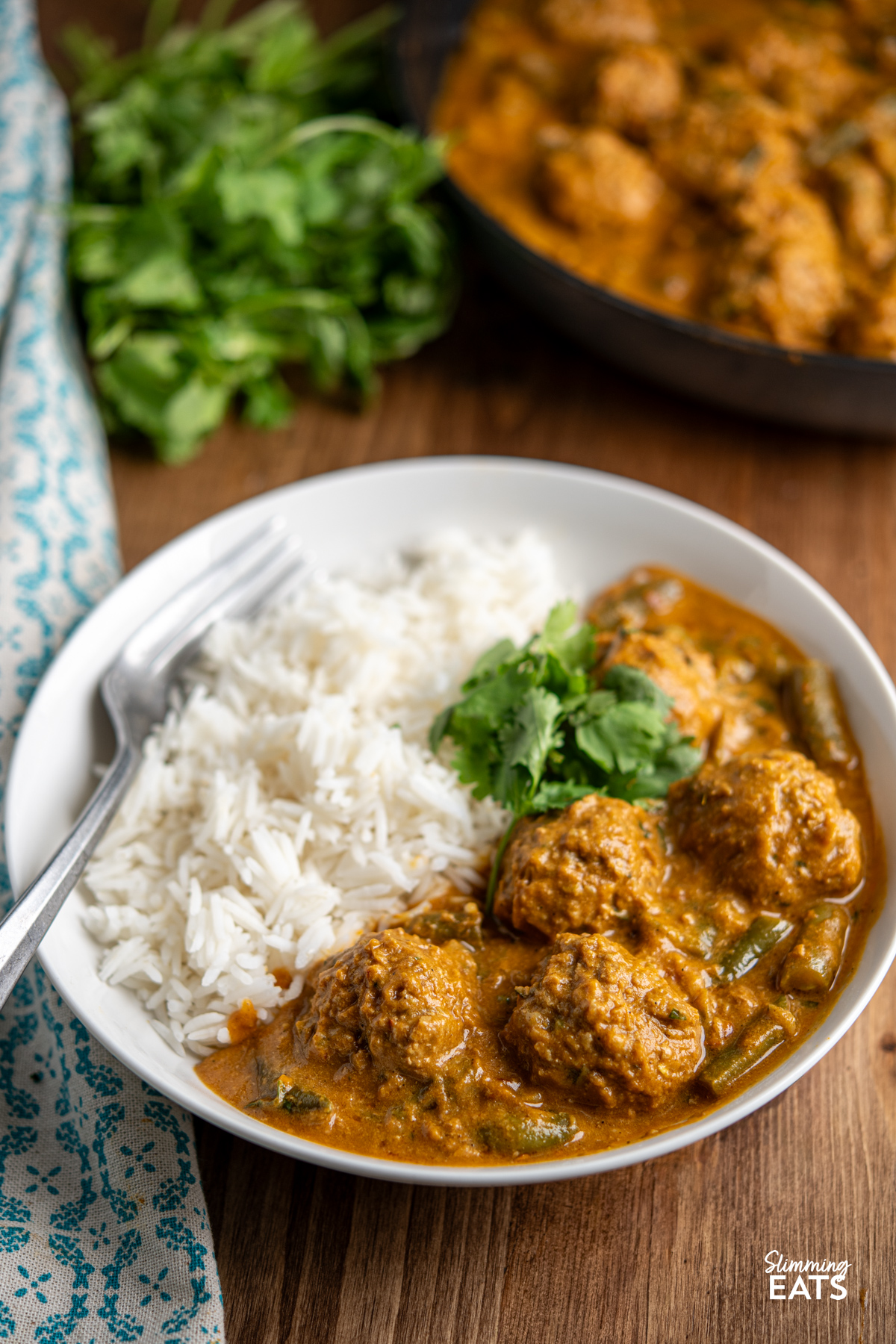 A Creamy Coconut Beef Meatball Curry - delicious tender meatballs with hidden veg in an amazing coconut sweet potato sauce. Gluten free, dairy free, paleo, whole30, Slimming and Weight Watchers friendly coconut beef meatballs curry in white bowl with rice and coriander