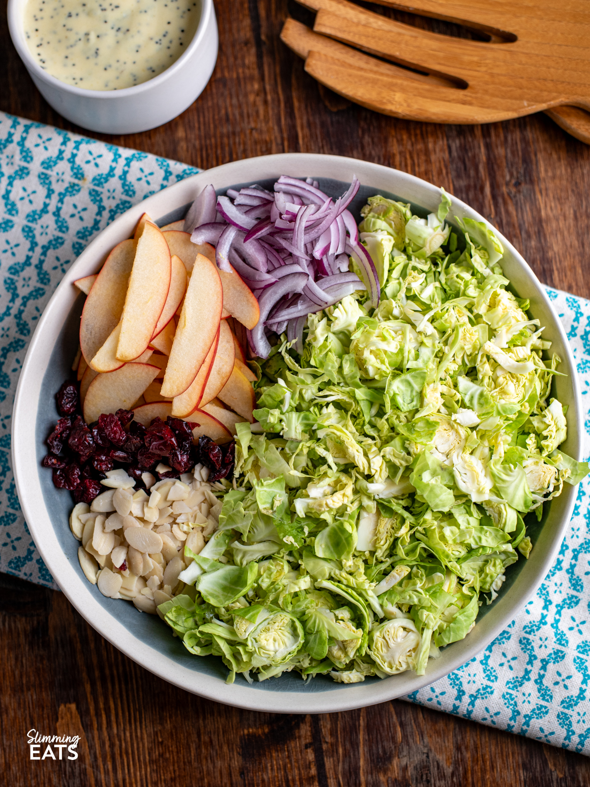 Brussels Sprouts Salad ingredients in a bowl ready to be mixed with dressing on side.