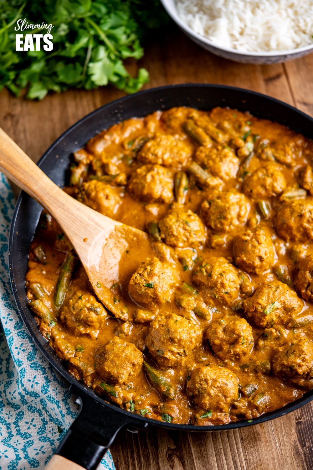 coconut beef meatball curry in black frying pan on wooden board