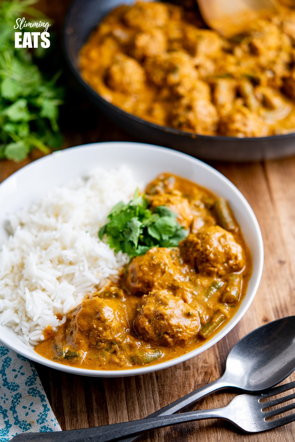 coconut beef meatballs curry in white bowl with rice and coriander