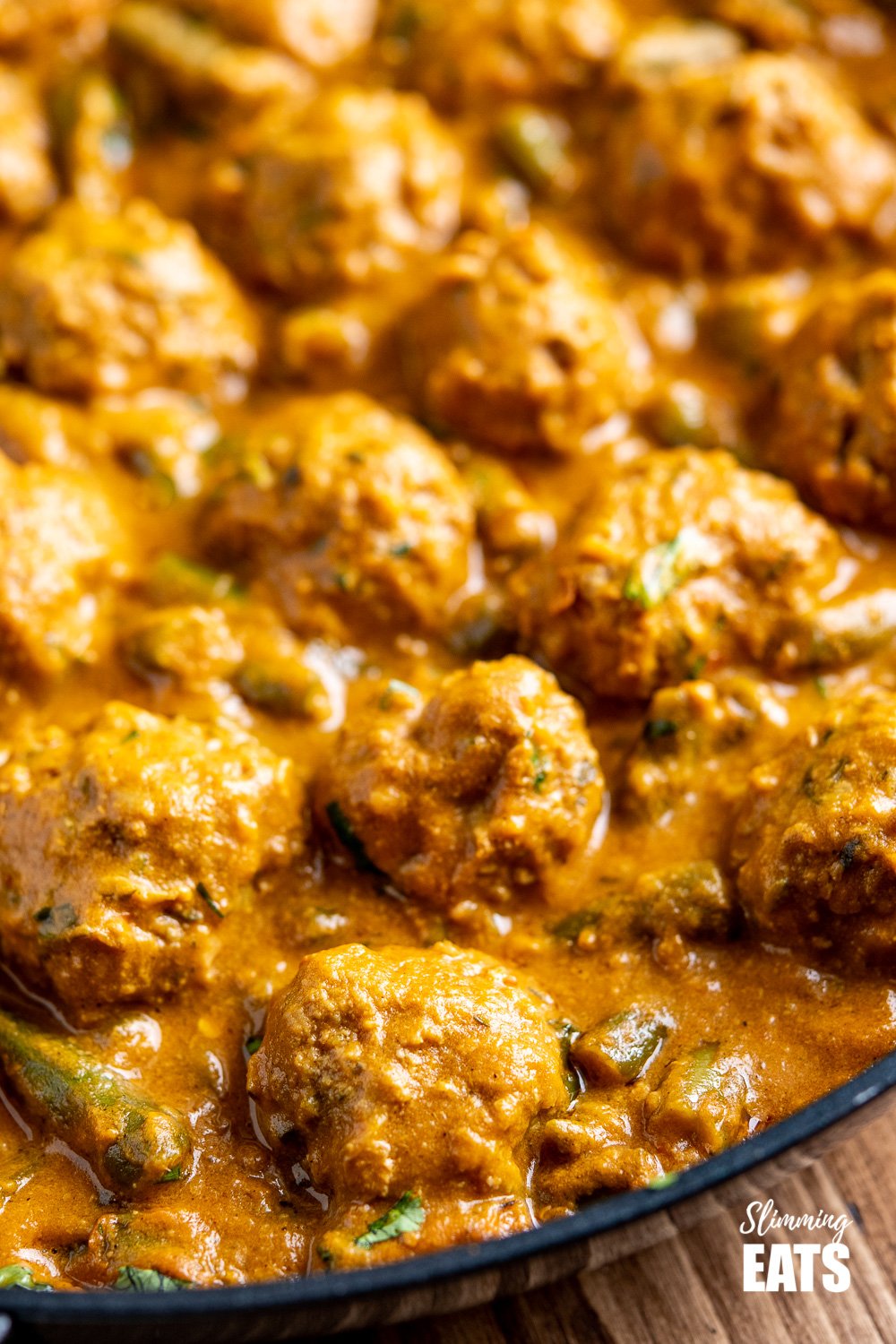 A Creamy Coconut Beef Meatball Curry - delicious tender meatballs with hidden veg in an amazing coconut sweet potato sauce. Gluten free, dairy free, paleo, whole30, Slimming and Weight Watchers friendly close up of coconut beef meatball curry in black frying pan
