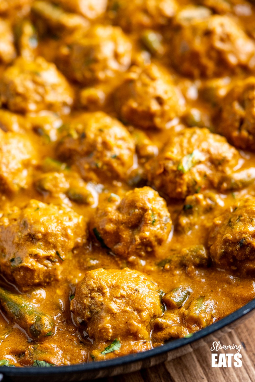 close up of coconut beef meatball curry in black frying pan