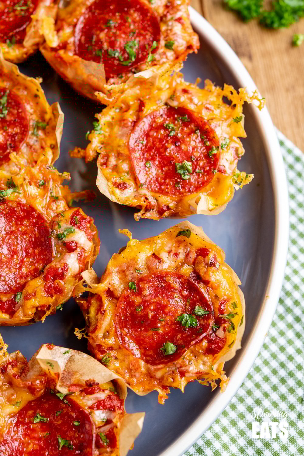 Drool-worthy Pepperoni Pizza Egg Bites - the mini cheesy bites are perfect for parties, tasters, lunches. Slimming and Weight Watchers friendly close up of Pepperoni Pizza Egg Bites on a blue plate