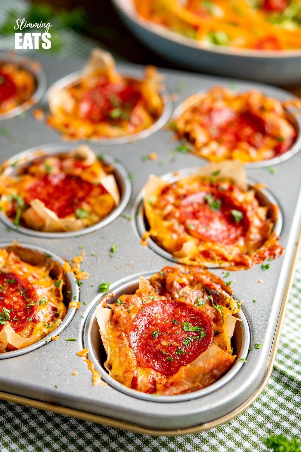 Drool-worthy Pepperoni Pizza Egg Bites - the mini cheesy bites are perfect for parties, tasters, lunches. Slimming and Weight Watchers friendly Pepperoni Pizza Egg Bites in a muffin tray on green checked towel