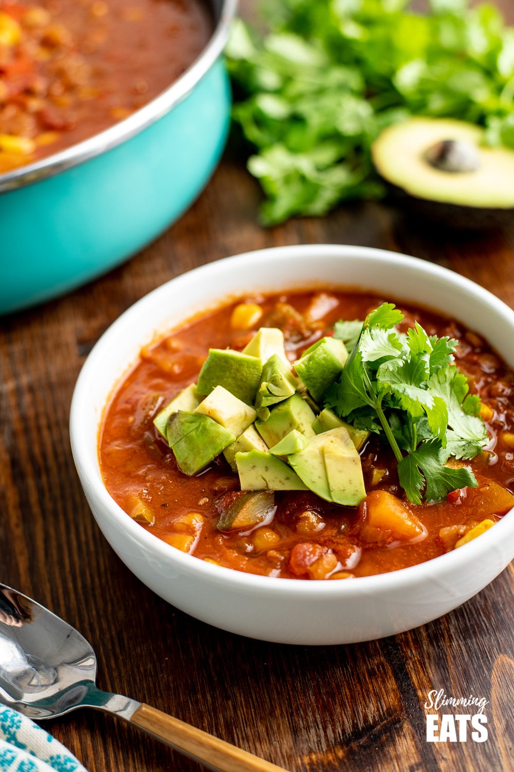 taco lentil soup in white bowl topped with avocado and cilantro