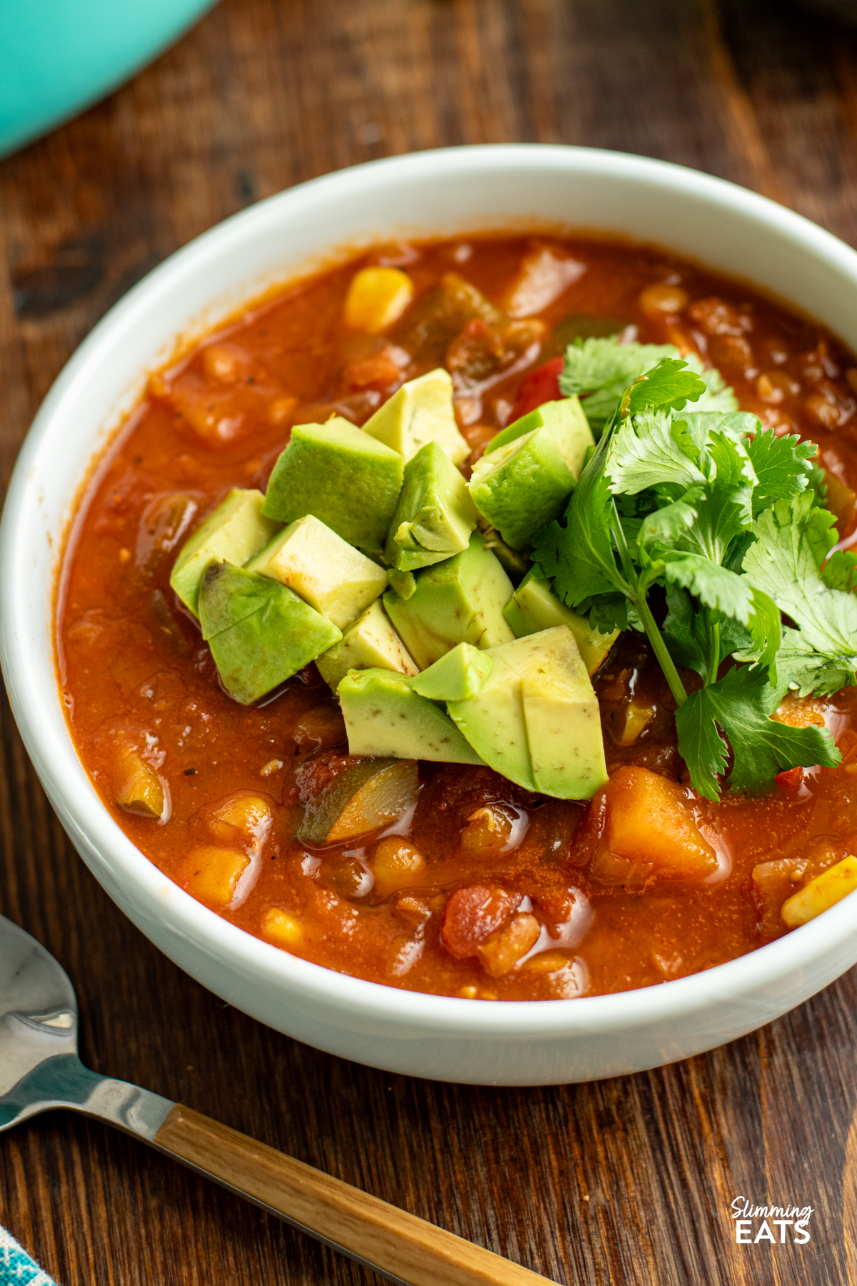 Taco Lentil Soup - the delicious spicy flavour of tacos using lentils instead of meat for a filling hearty meal that even the kids will enjoy. Gluten Free, Dairy Free, Vegan, Slimming and Weight Watchers friendly taco lentil soup in white bowl with wooden spoon topped with avocado and cilantro