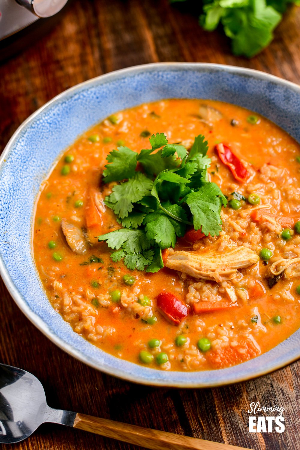 Delicious Instant Pot Thai Chicken Rice Soup - a fragrant soup that is super quick and easy to make. Gluten Free, Dairy Free, Slimming Eats and Weight Watchers friendly close up of thai chicken rice soup in blue bowl on wooden board.