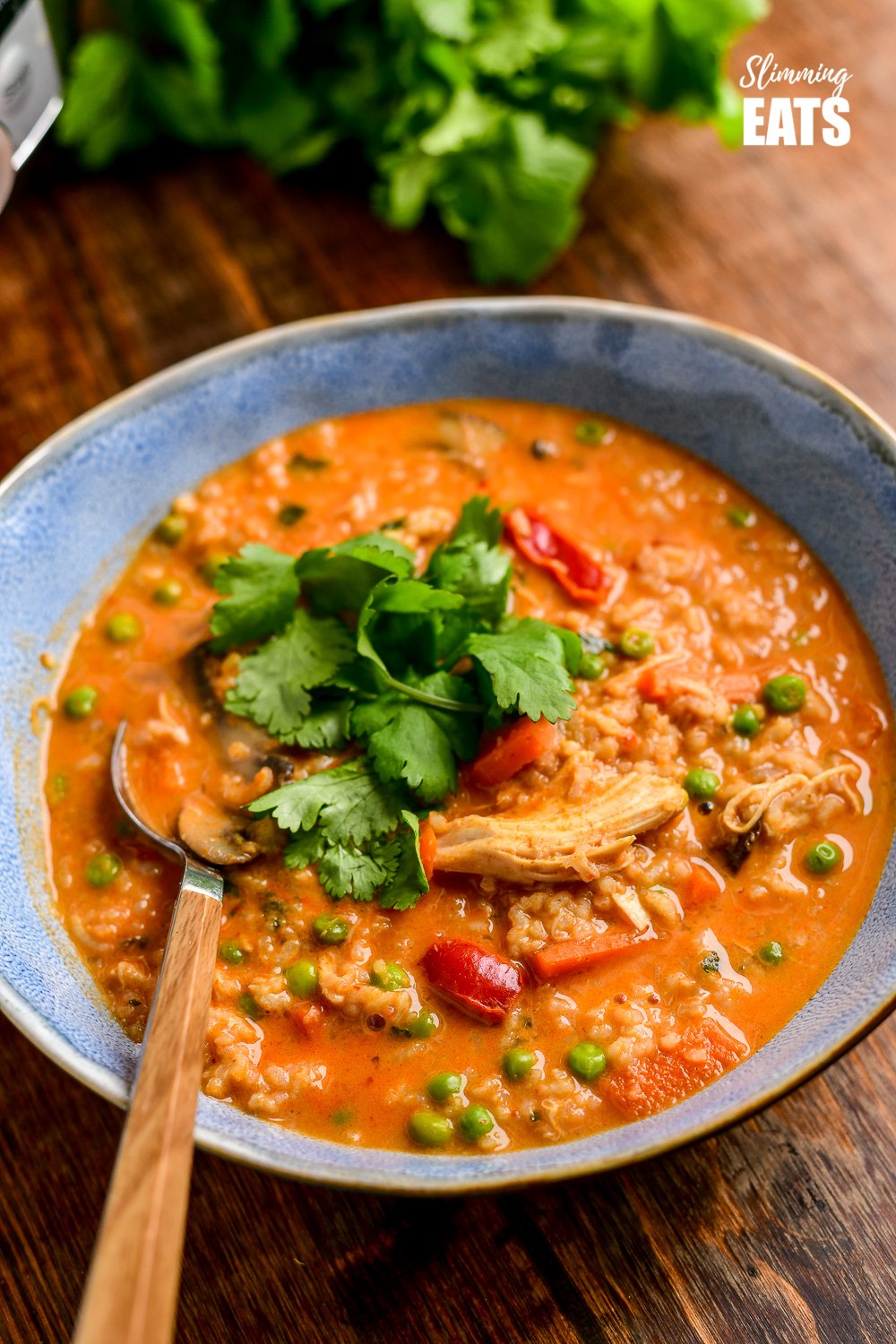 thai chicken rice soup in blue bowl with spoon