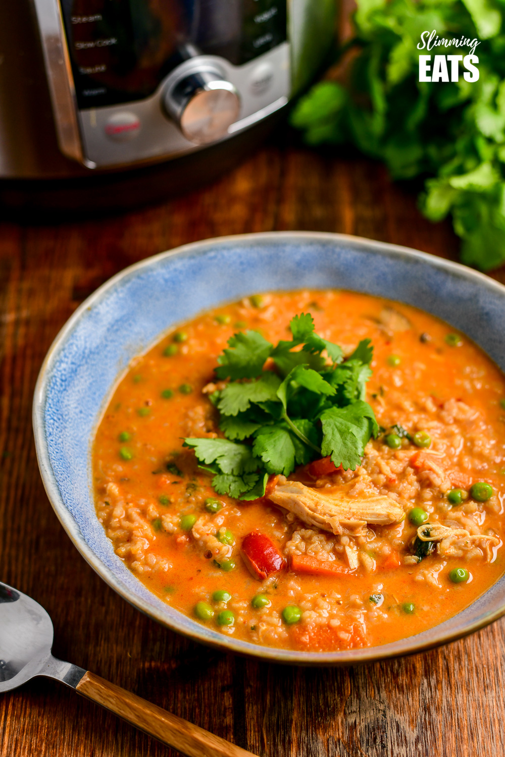 Thai chicken rice soup in blue bowl on wooden board with instant pot in background