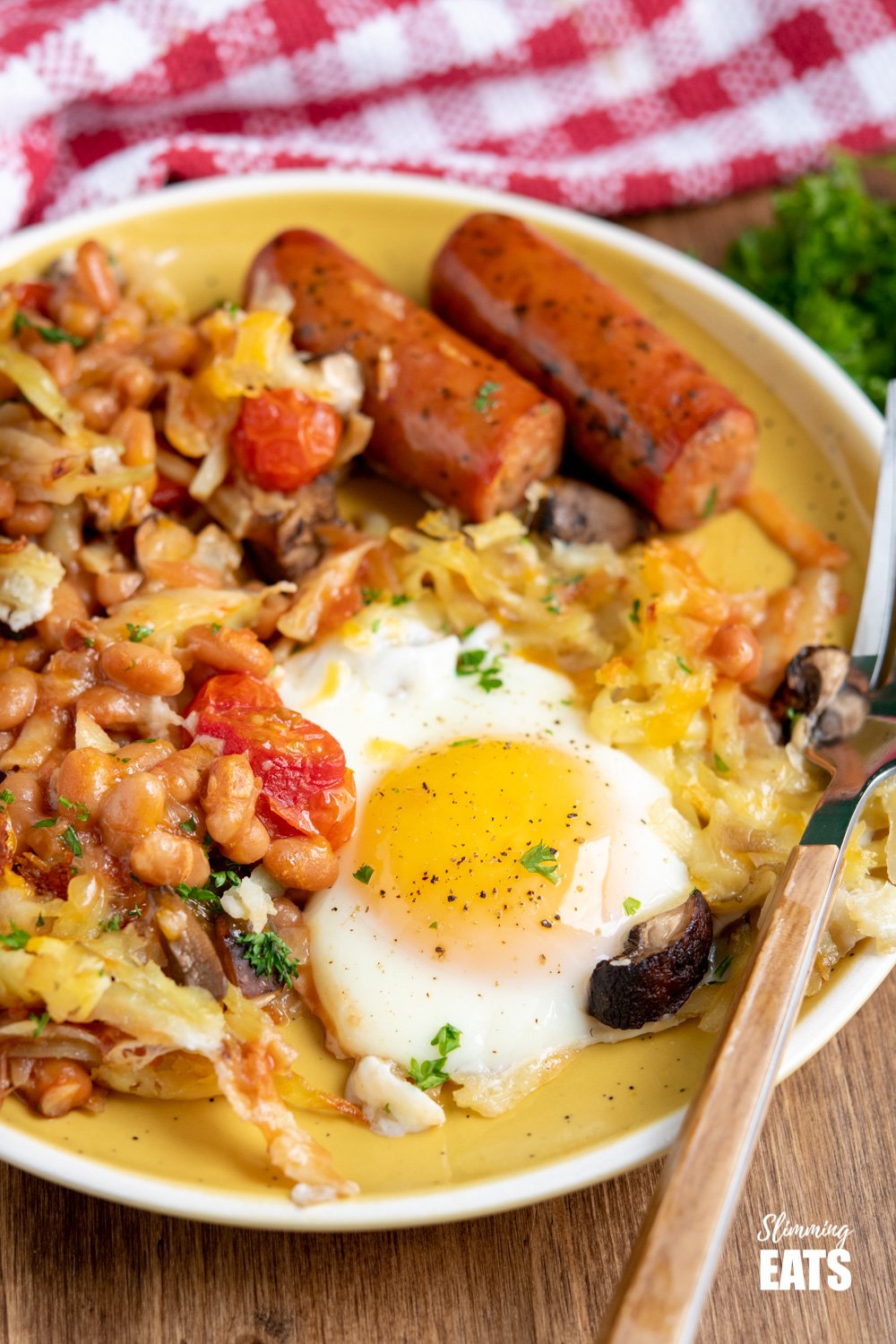 all day breakfast tray bake served up on a yellow plate with wooden handled fork. 