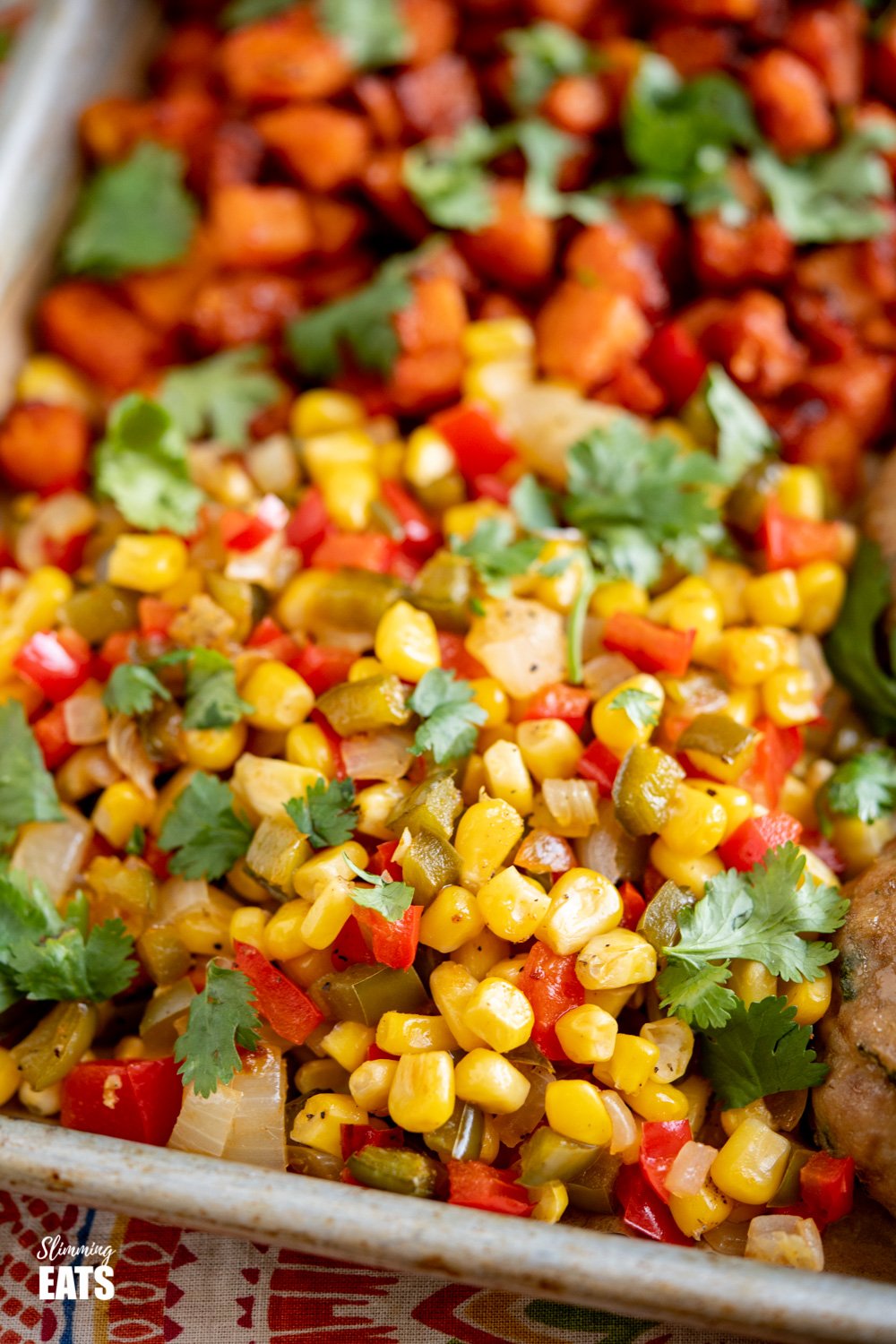 Honey Garlic Chicken Burger Tray Bake - tasty chicken burgers flavoured with honey and garlic all cooked on one tray with roasted butternut squash, peppers, onion and corn. Gluten Free, Slimming Eats and Weight Watchers friendly close up of roasted corn, peppers and onion on baking tray
