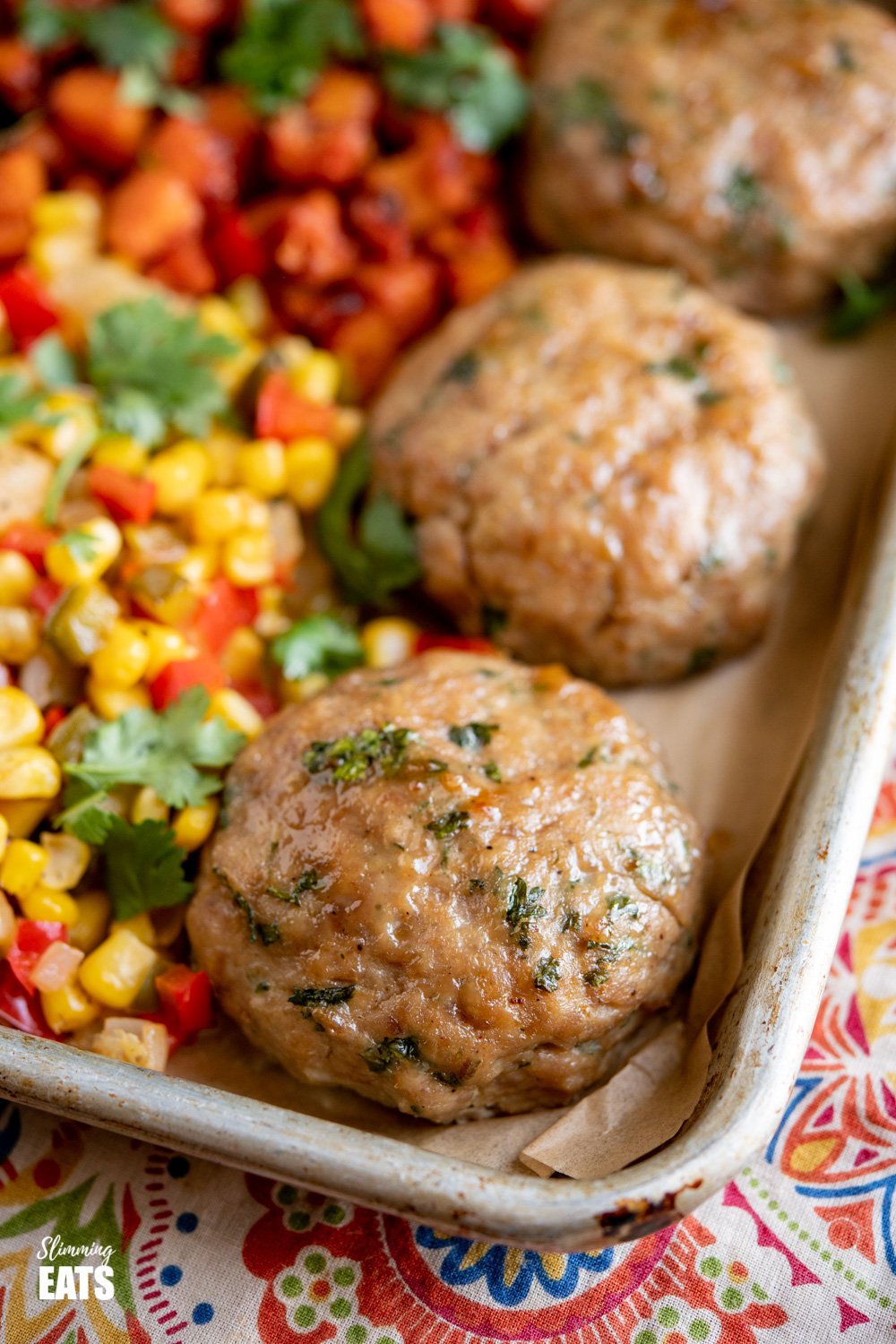 Honey Garlic Chicken Burger Tray Bake - tasty chicken burgers flavoured with honey and garlic all cooked on one tray with roasted butternut squash, peppers, onion and corn. Gluten Free, Slimming Eats and Weight Watchers friendly close up of chicken burgers on baking tray