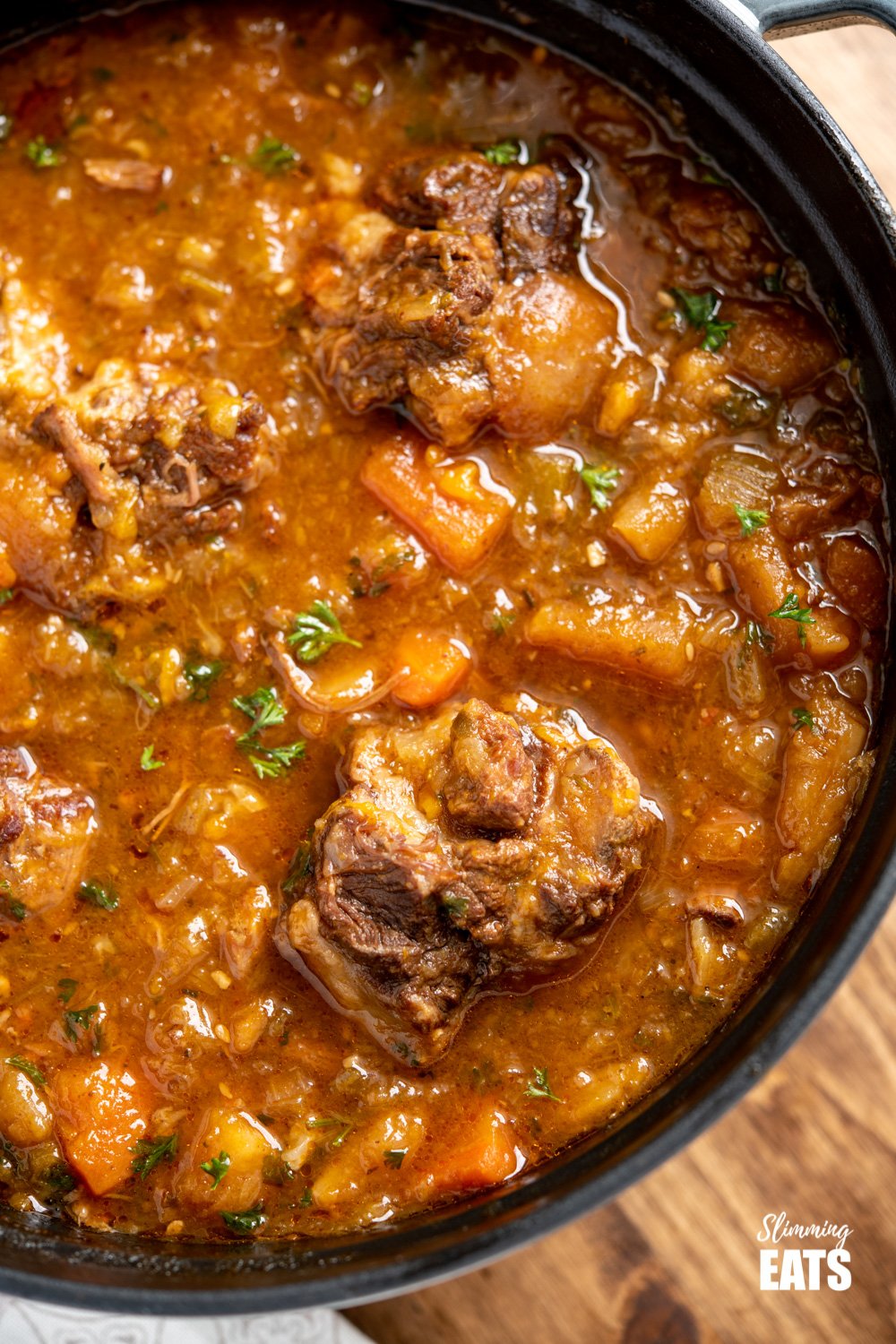 Hearty Oxtail Stew - fall off the bone tender oxtails cooked in a delicious vegetable packed broth that is just pure comfort in a bowl. Gluten Free, Dairy Free, Paleo, Whole30, Weight Watchers and Slimming World friendly close up of Hearty Oxtail Stew in a grey staub cast iron pot