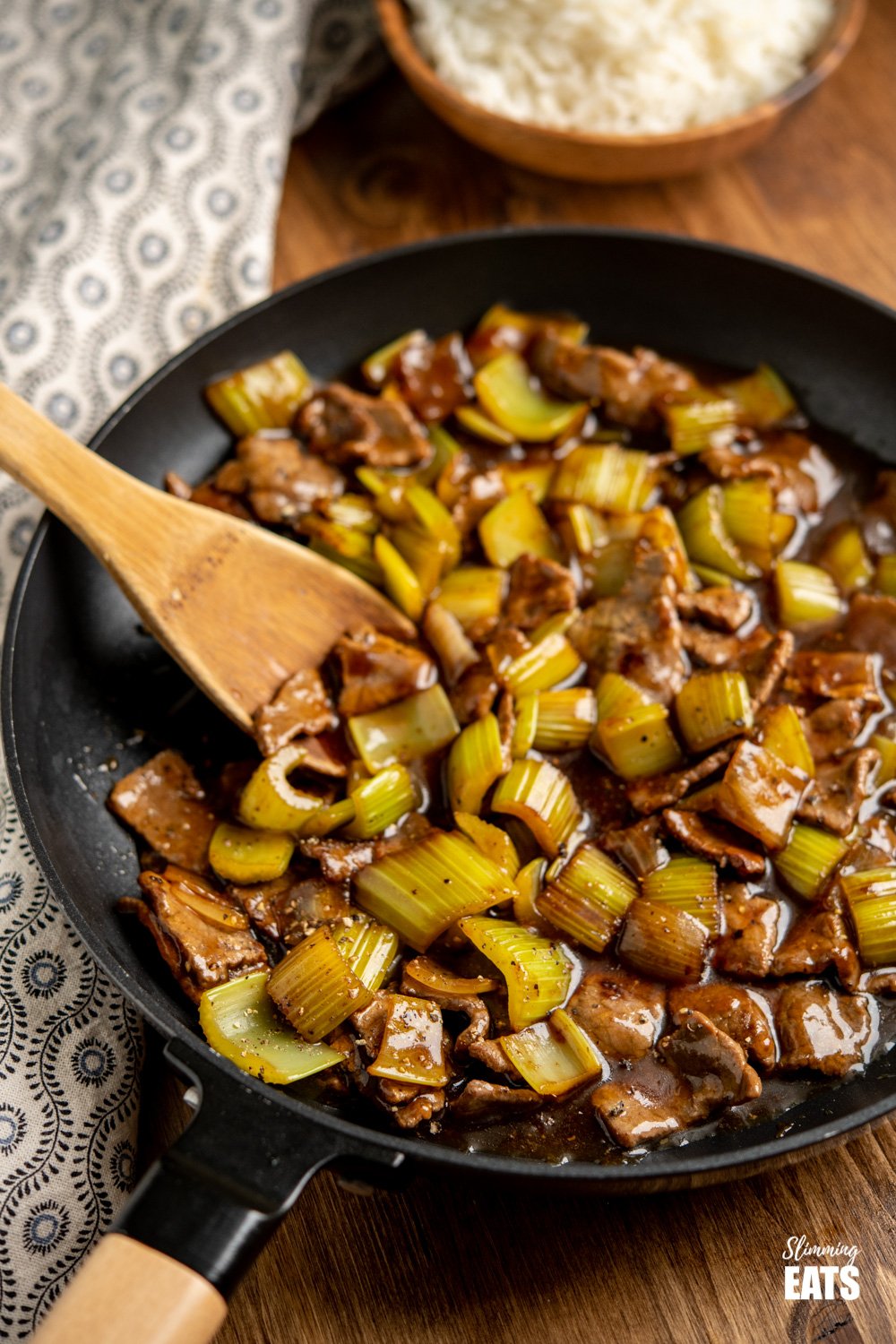 Chinese black pepper beef in black frying pan with wooden spoon