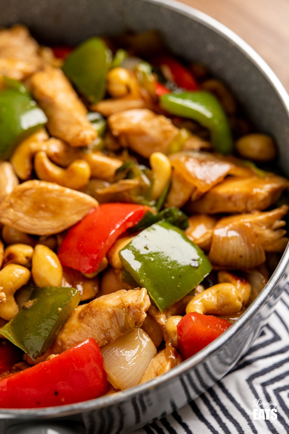 Chinese Cashew Chicken - amazingly tender pieces of chicken in a delicious sauce with cashew nuts and vegetables. Dairy Free, Slimming Eats and Weight Watchers friendly. close up of Chinese cashew chicken in a grey frying pan