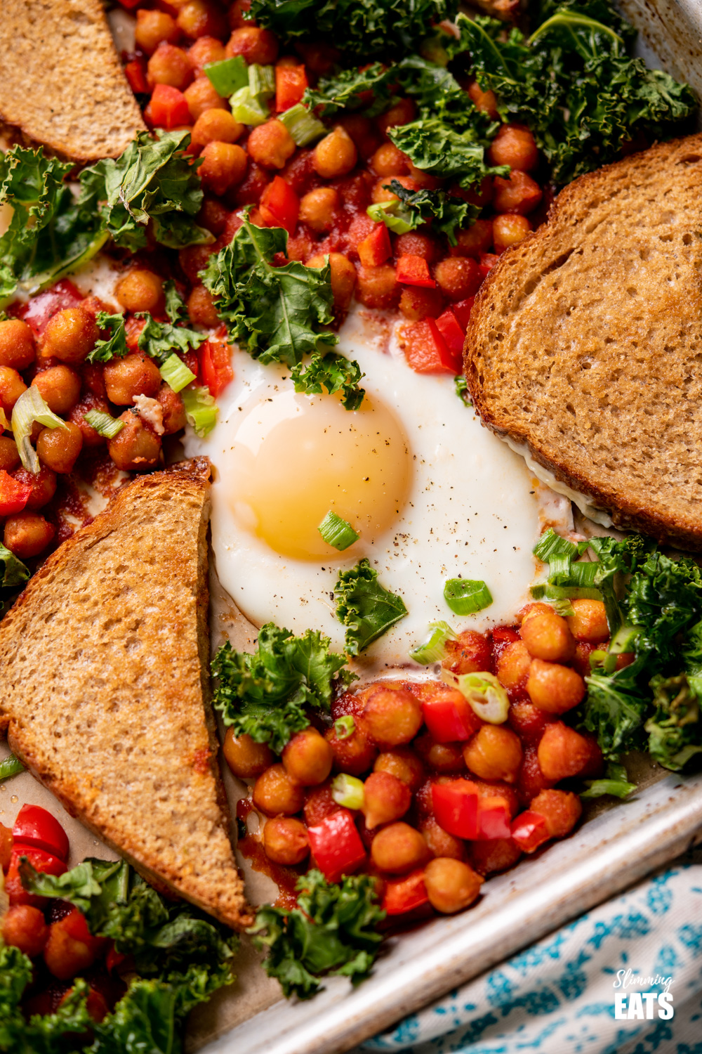 close up of chickpeas, egg and toast with kale on tray