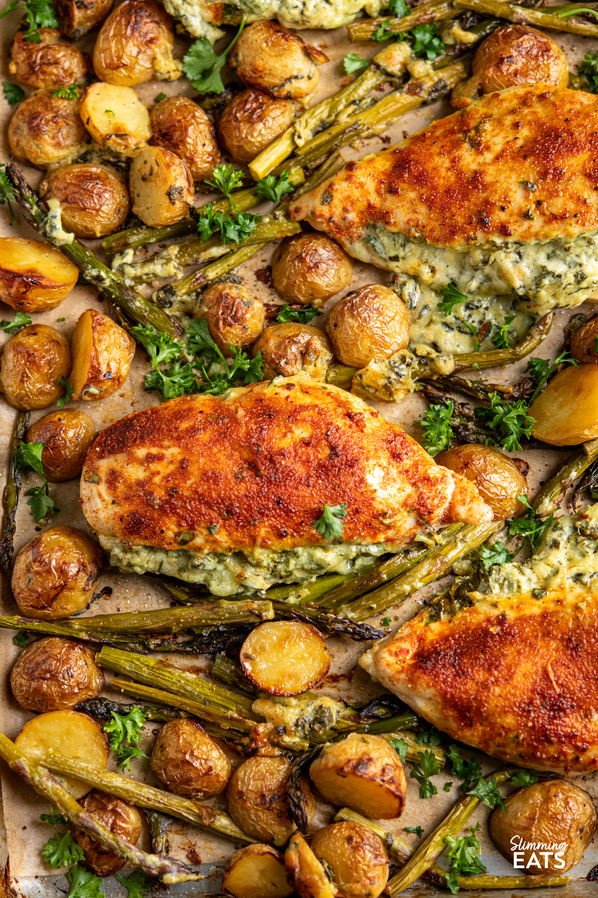 Creamy Cheesy Spinach Stuffed Chicken Tray Bake - Tender Juicy Chicken Breasts with a Creamy Parmesan Spinach Stuffing all baked on one tray with Baby Yukon Gold Potatoes and Asparagus. Gluten-Free, Slimming Eats and Weight Watchers friendly close up of Creamy Cheesy Spinach Stuffed Chicken on a baking tray