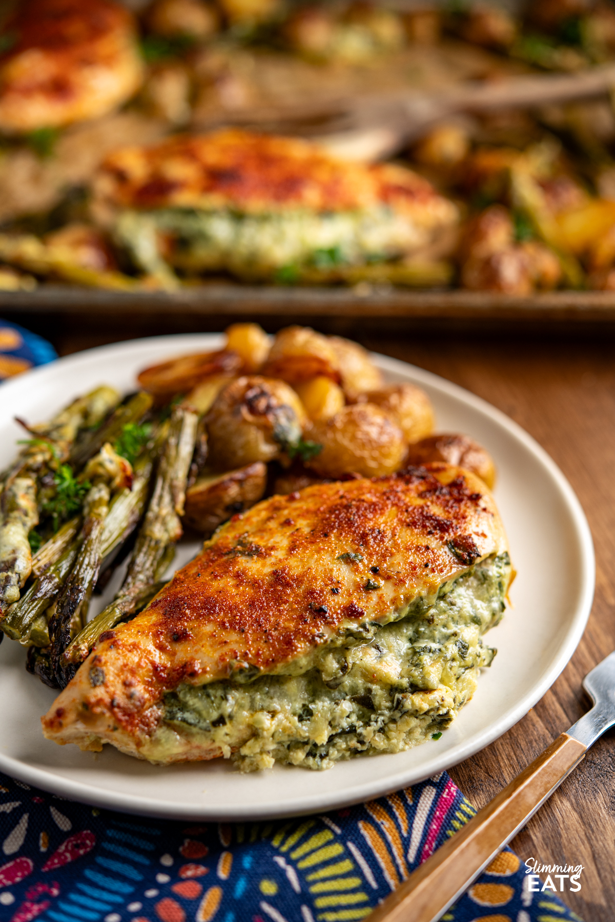 Creamy Cheesy Spinach Stuffed Chicken Tray Bake - Tender Juicy Chicken Breasts with a Creamy Parmesan Spinach Stuffing all baked on one tray with Baby Yukon Gold Potatoes and Asparagus. Gluten-Free, Slimming Eats and Weight Watchers friendly Creamy Cheesy Spinach Stuffed Chicken on plate with asparagus and roasted baby potatoes