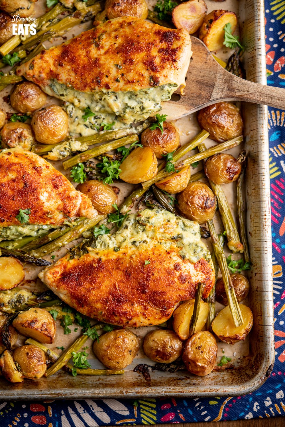 Creamy Cheesy Spinach Stuffed Chicken Tray Bake - Tender Juicy Chicken Breasts with a Creamy Parmesan Spinach Stuffing all baked on one tray with Baby Yukon Gold Potatoes and Asparagus. Gluten-Free, Slimming World and Weight Watchers friendly close up of Creamy Cheesy Spinach Stuffed Chicken on a baking tray