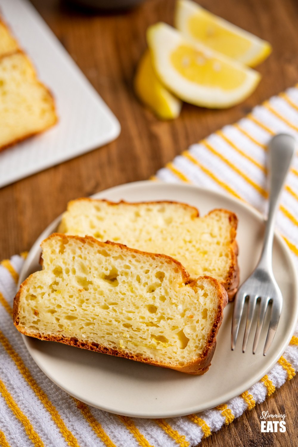 2 slices of lemon ricotta cake on cream plate with fork