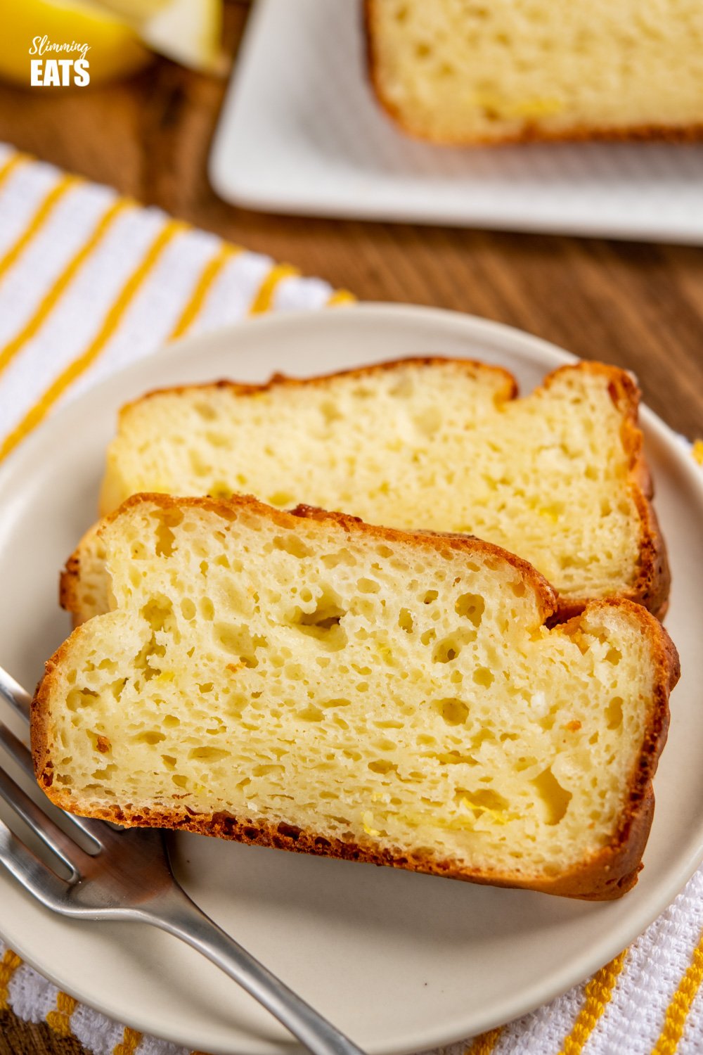 close up of 2 slices of lemon ricotta cake on cream plate