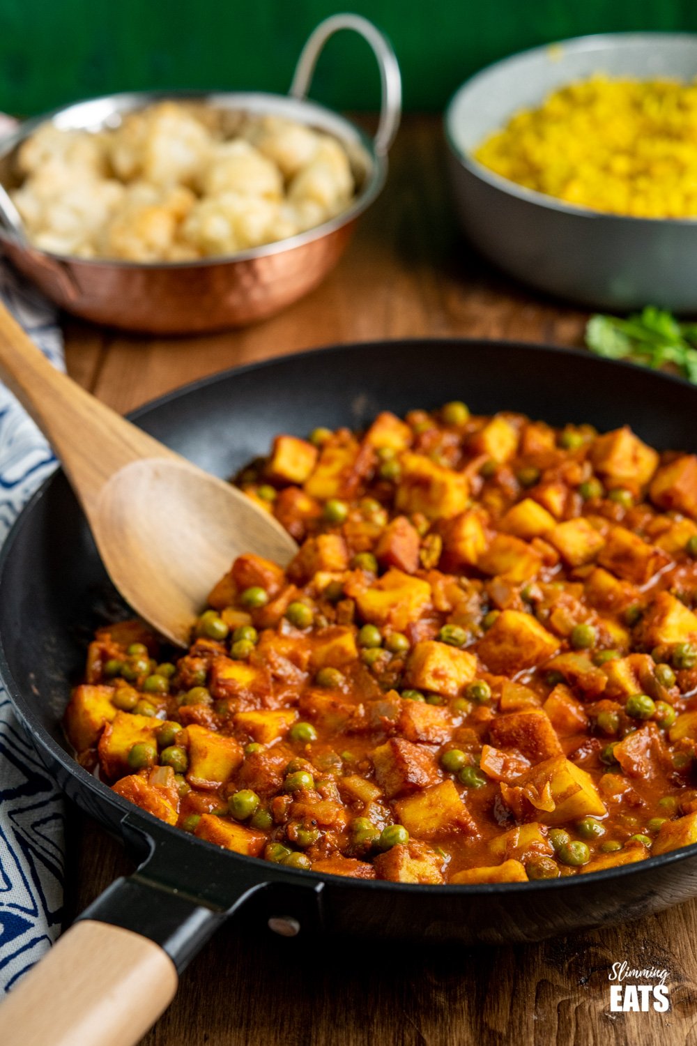 matar paneer curry in black frying pan with cauliflower and rice in background