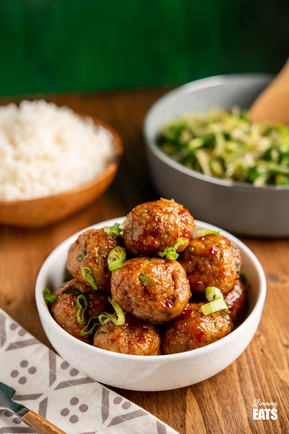 sweet chilli chicken meatballs in white bowl sprinkled with spring onion