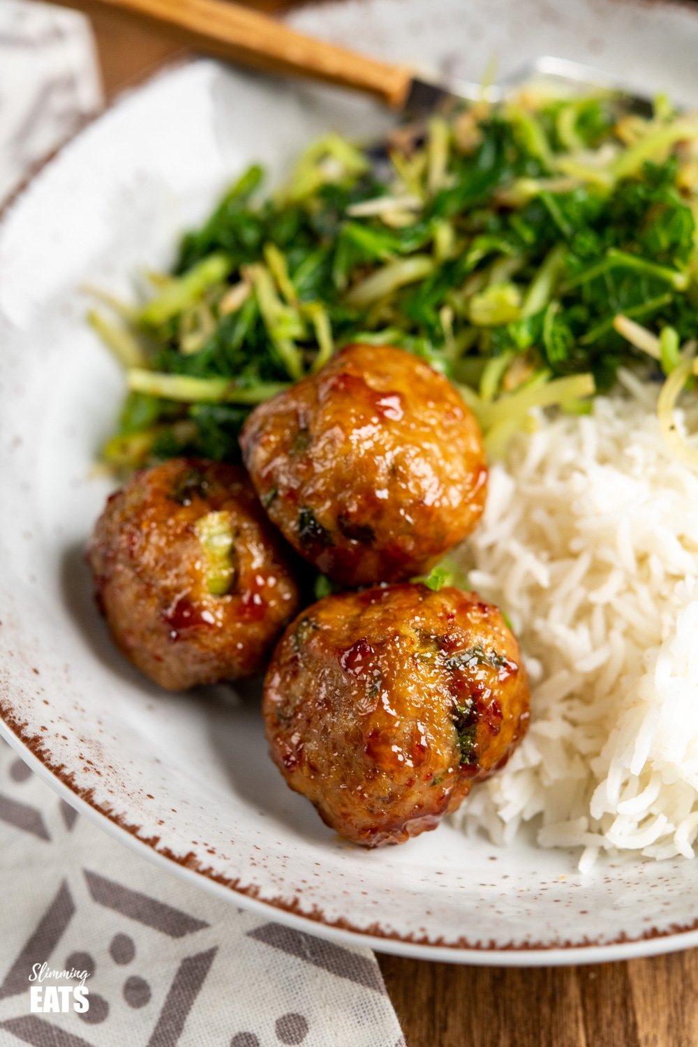 close up of sweet chilli chicken meatballs in bowl with rice and veggies